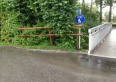 Wasserlache/Holzzaun/Straßenschild