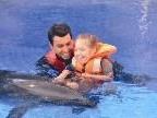Jennifer mit ihrem Therapeuten und dem Delphin während der Therapie im Sommer in der Türkei