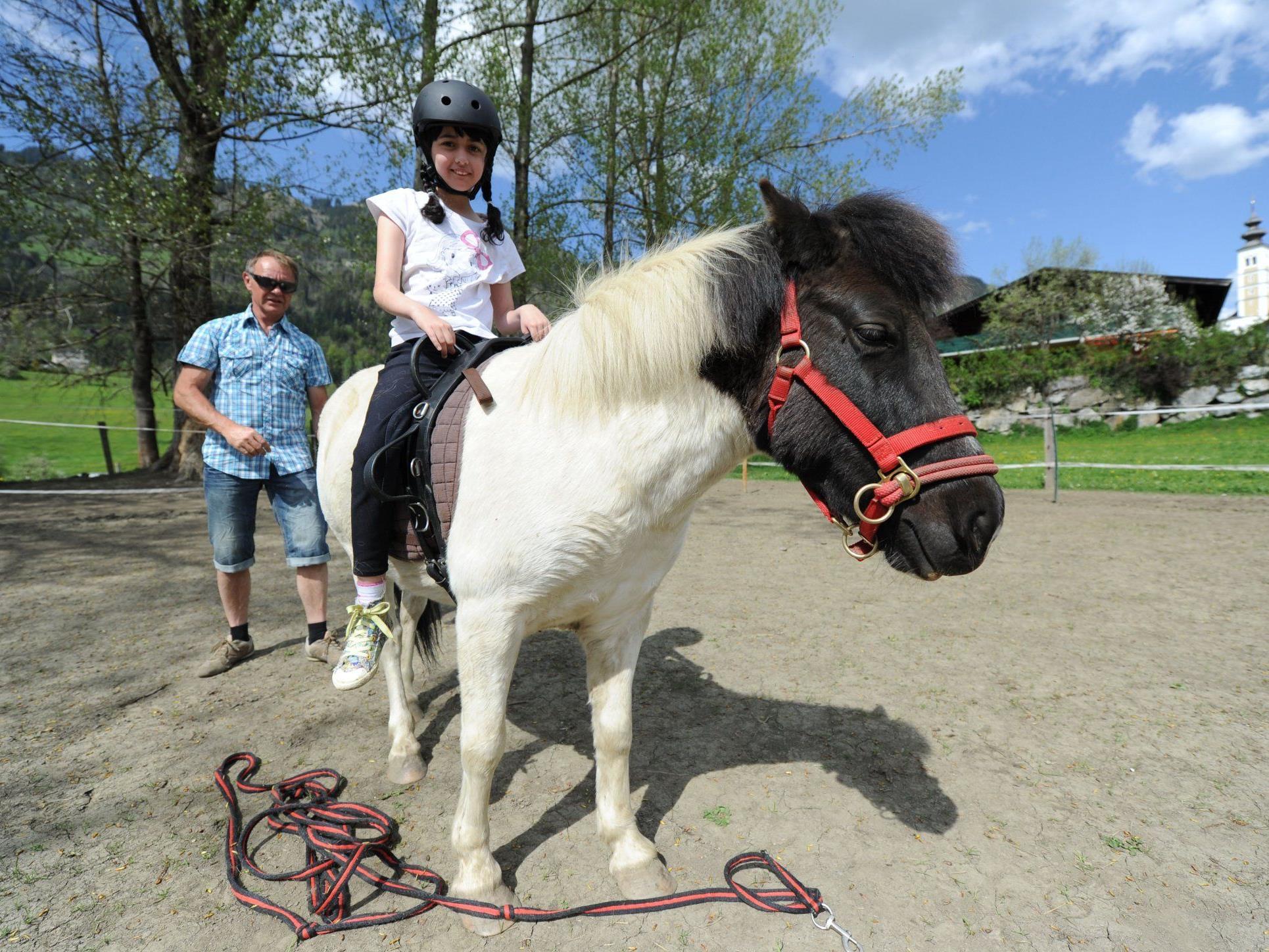 Die achtjährige Sabrina, die an Epilepsie und einer Entwicklungsstörung leidet, mit "Pferdeflüsterer" Heinz Aigner (l.) auf dem Therapiepferd "Kleiner Donner", am "Little Horseland for Kids" in St. Veit im Pongau.