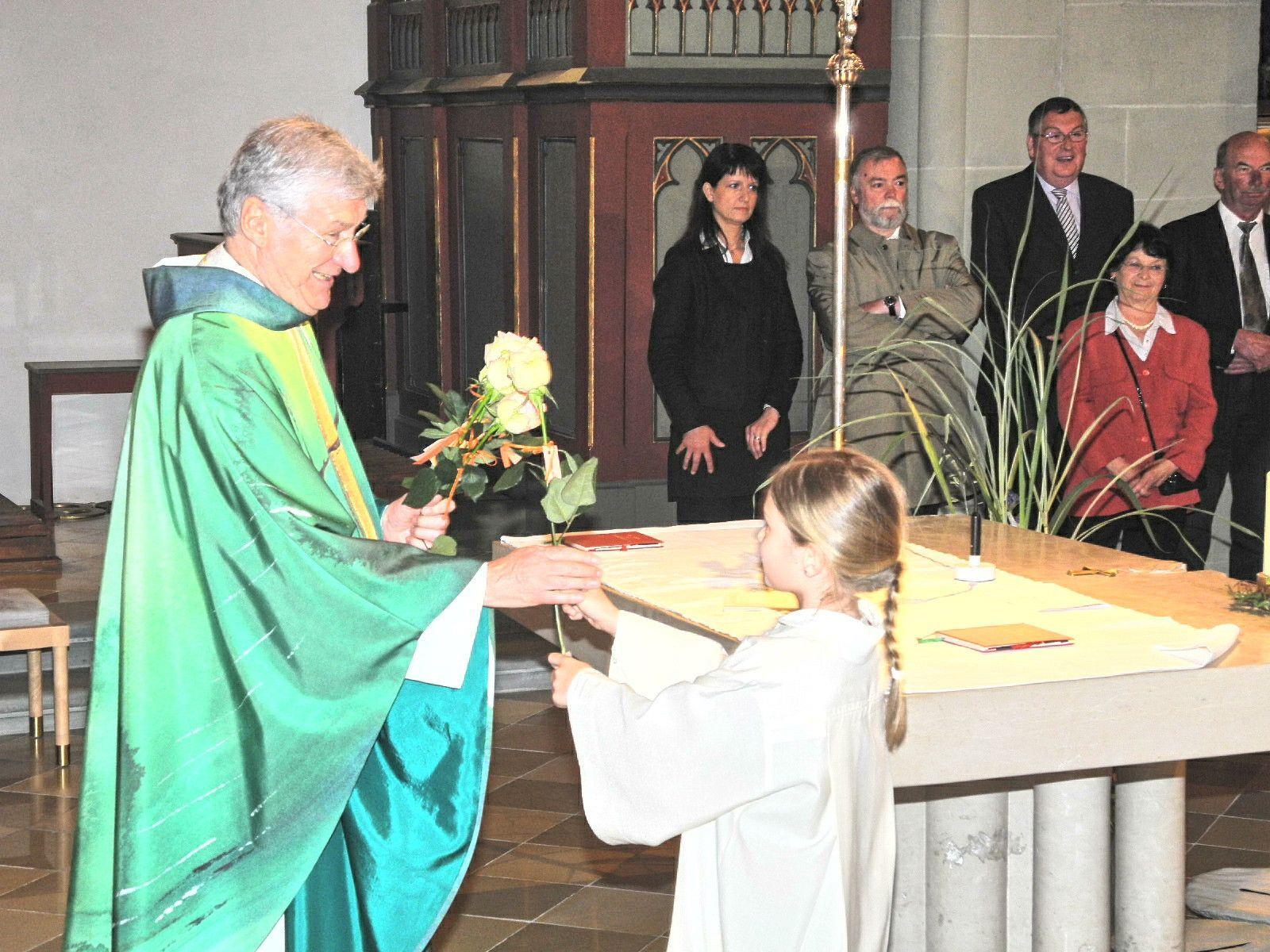 Eine Ministrantin überreicht Dompfarrer Rudolf Bischof eine Rose