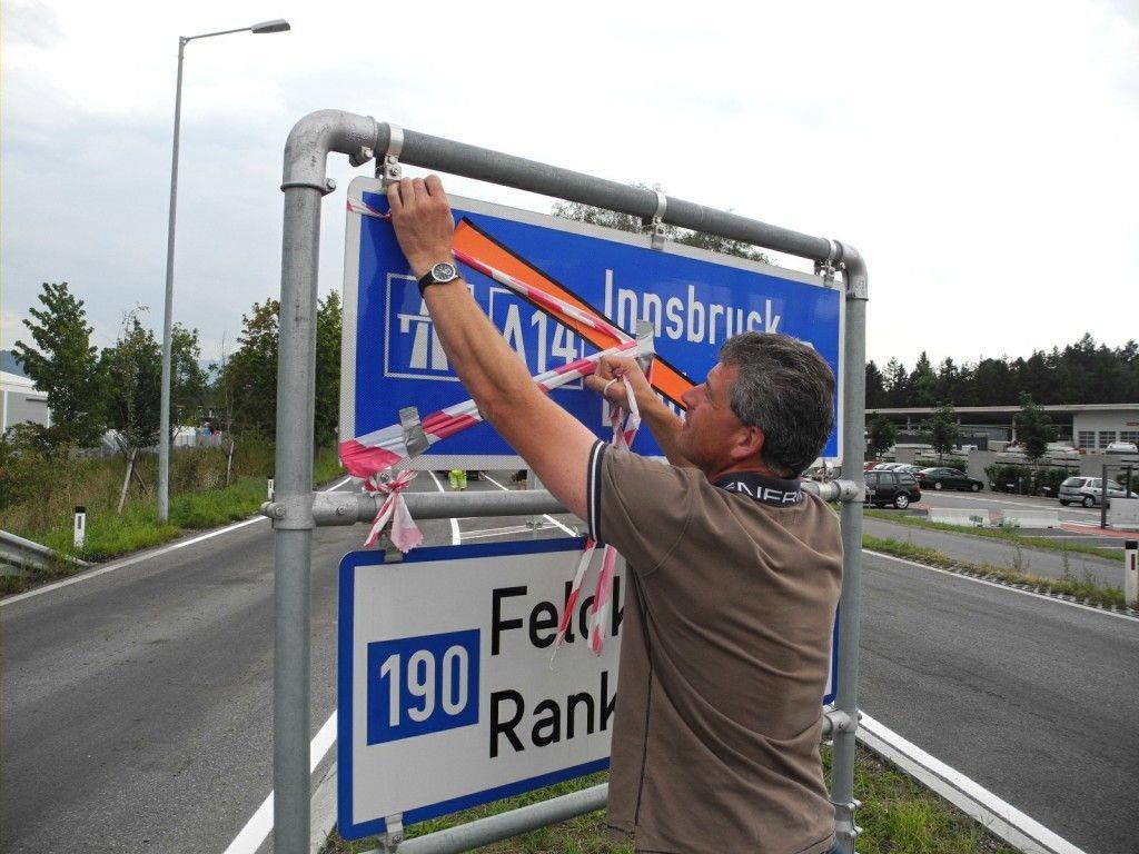 Wolfgang Lassnig von der Straßenbauabteilung entfernt die Bänder von den Straßenhinweistafeln und übergibt damit die neue Frutzbrücke den Autofahrern.