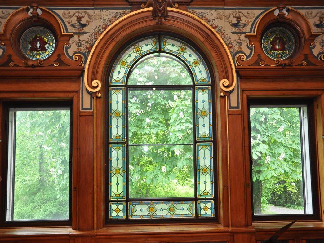 Die Symbole Spindel und Glühbirne zieren die Fenster im historischen Musiksaal der Villa Grünau.
