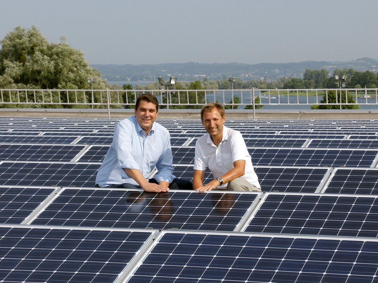 Harald Köhlmeier und Gemeinderat Peter Bildstein inmitten von Photovoltaikmodulen der Sporthalle.