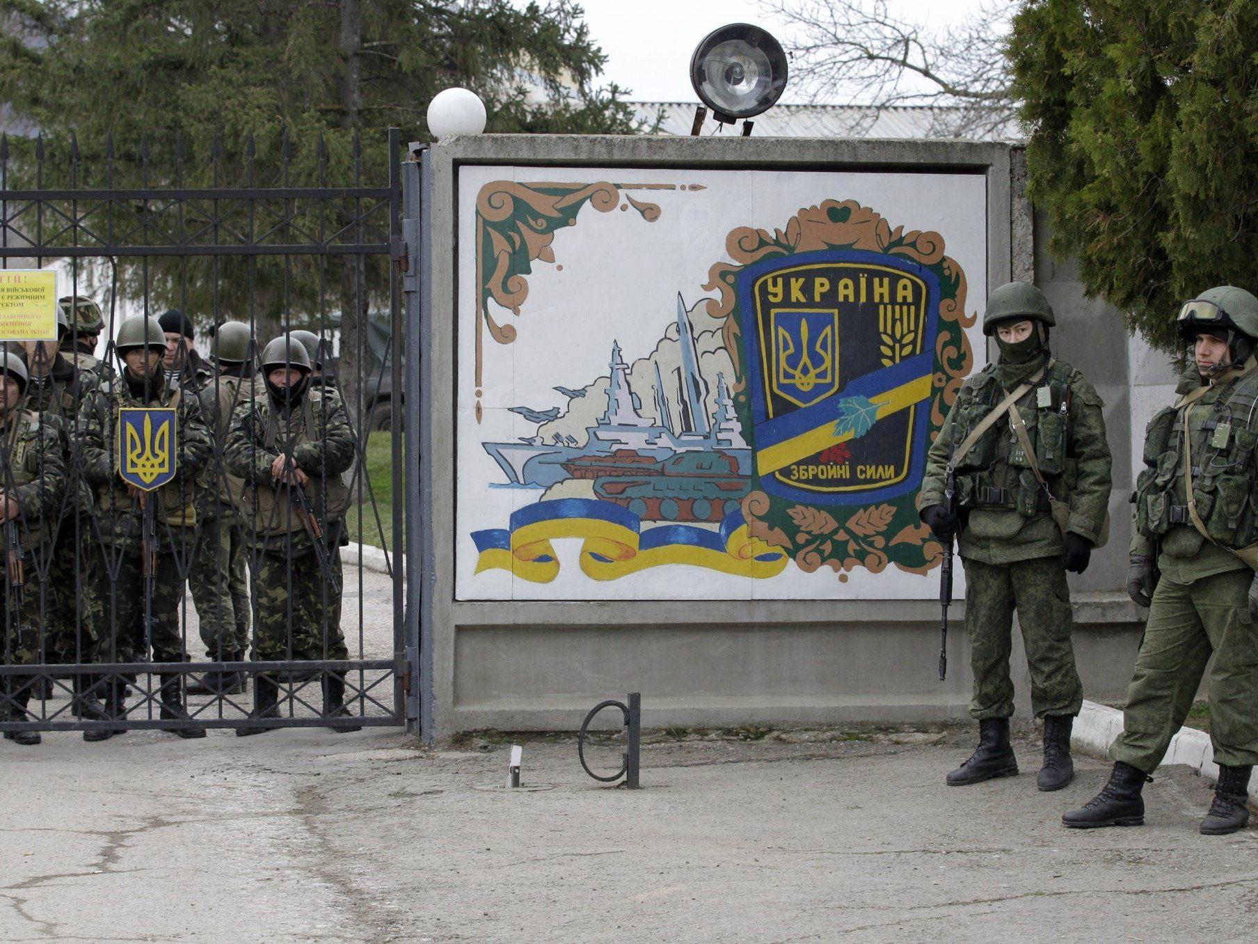 Unidentifizierte Truppen (r.) hindern ukrainische Truppen (l.) am Verlassen ihres Stützpunktes.