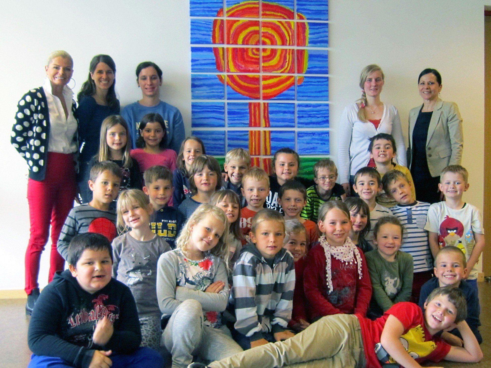 Direktorin Silvia Benzer mit Caroline Rusch, den Kindern und Lehrerinnen vor dem „Hundertwasser-Baum“.