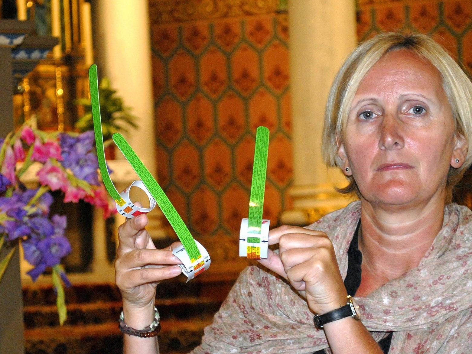 Mag. Iris Feuerstein, ehrenamtliche Mitarbeiterin der Caritas, zeigt hier Armbänder für unterernährte Menschen.