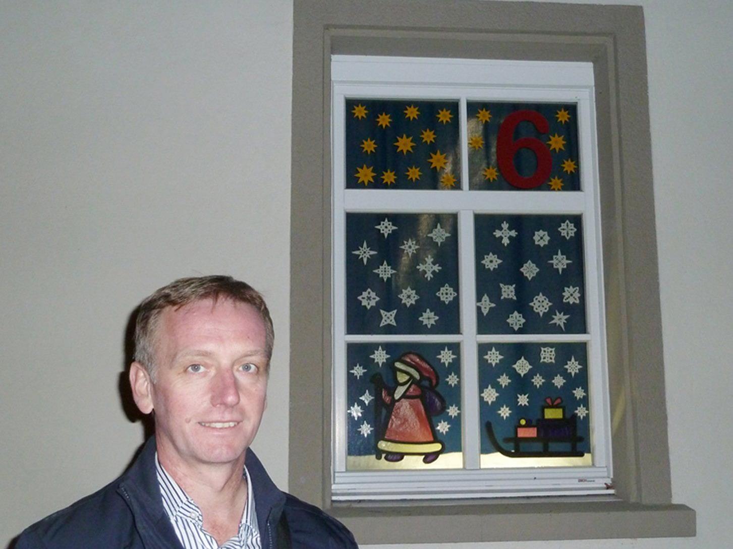 Christoph Jagg, Direktor der Volksschule Markt, vor einem beleuchteten Adventfenster.