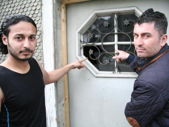 Bewohner des Asylheims zeigen die zerbrochene Scheibe
