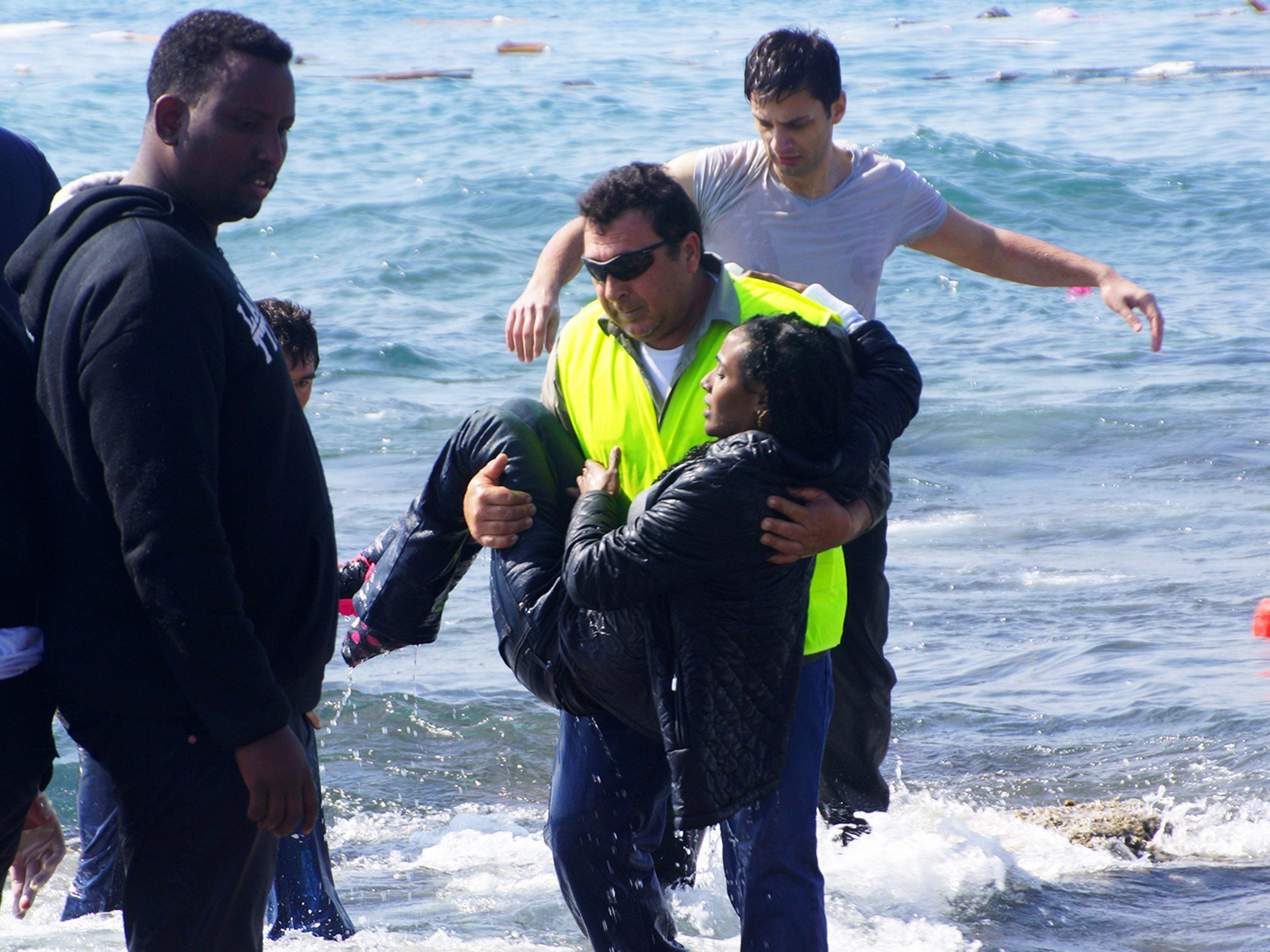 Ein Helfer rettet eine Frau aus den Fluten. Drei Schiffe mit Flüchtlingen sollen allein am Montag in Seenot geraten sein.