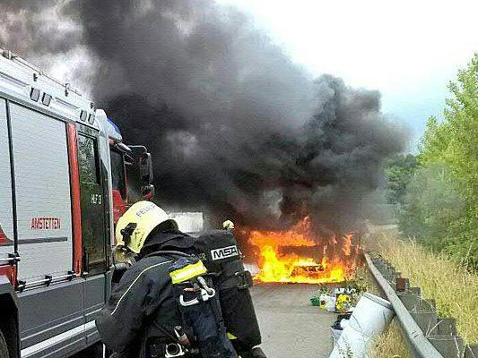 Ein Feuerwehrmann vor dem brennenden Pkw auf der A1