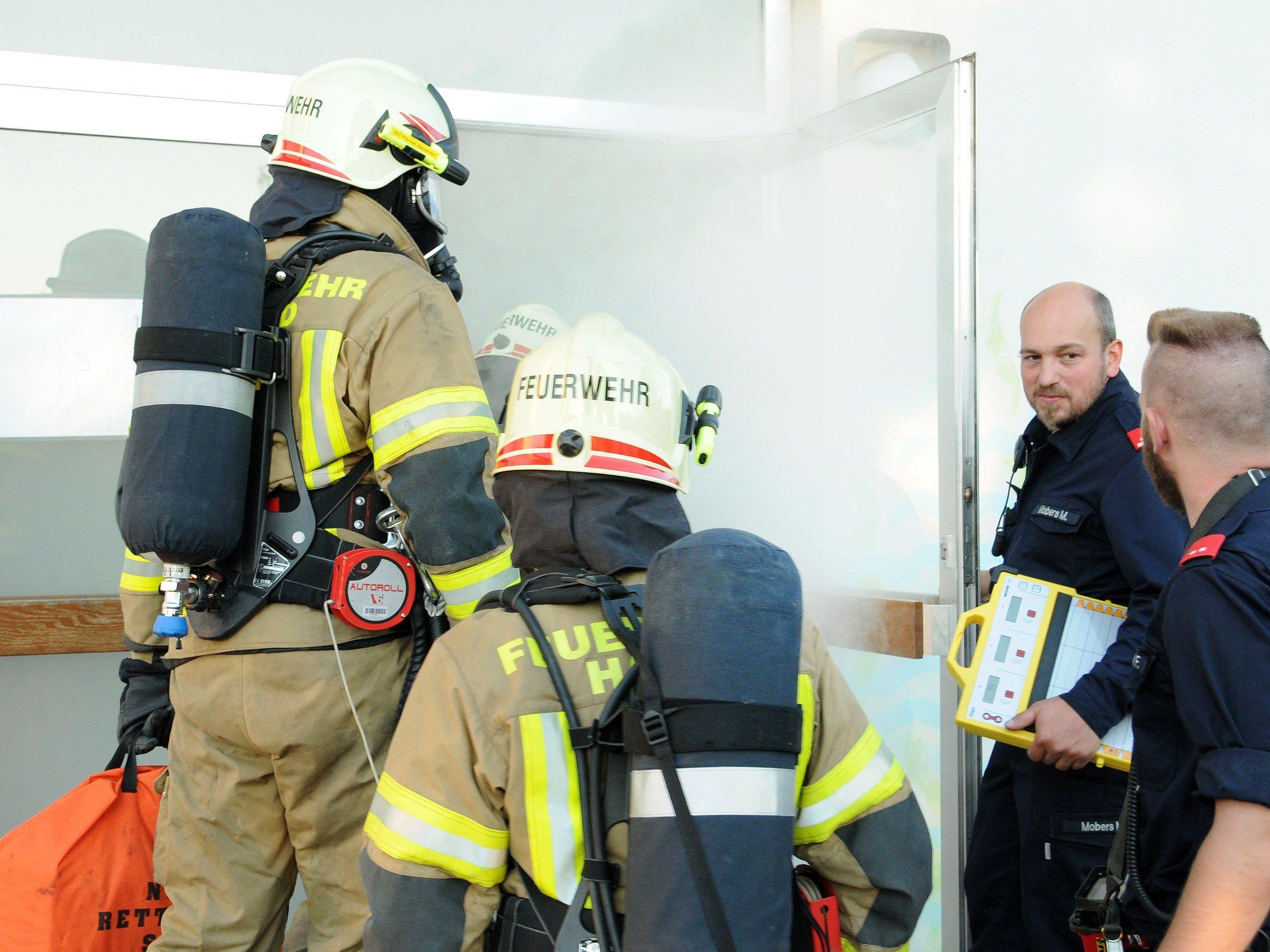 Feuerwehrmänner mit schwerem Atemschutz dringen in das völlig vernebelte Schulhaus ein.