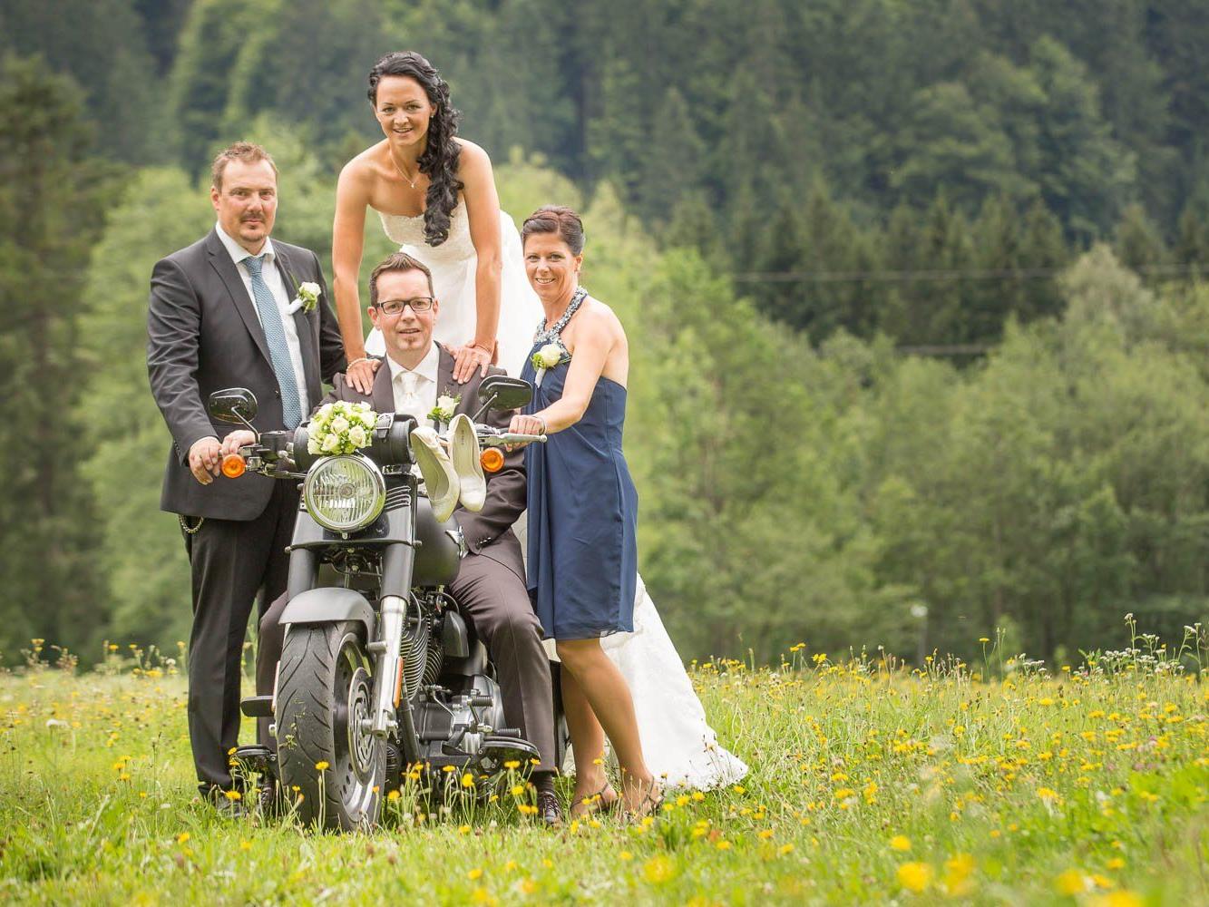 Das frisch vermählte Paar, hier mit seinen Trauzeugen und mit Motorrad, fahren ins Eheglück.