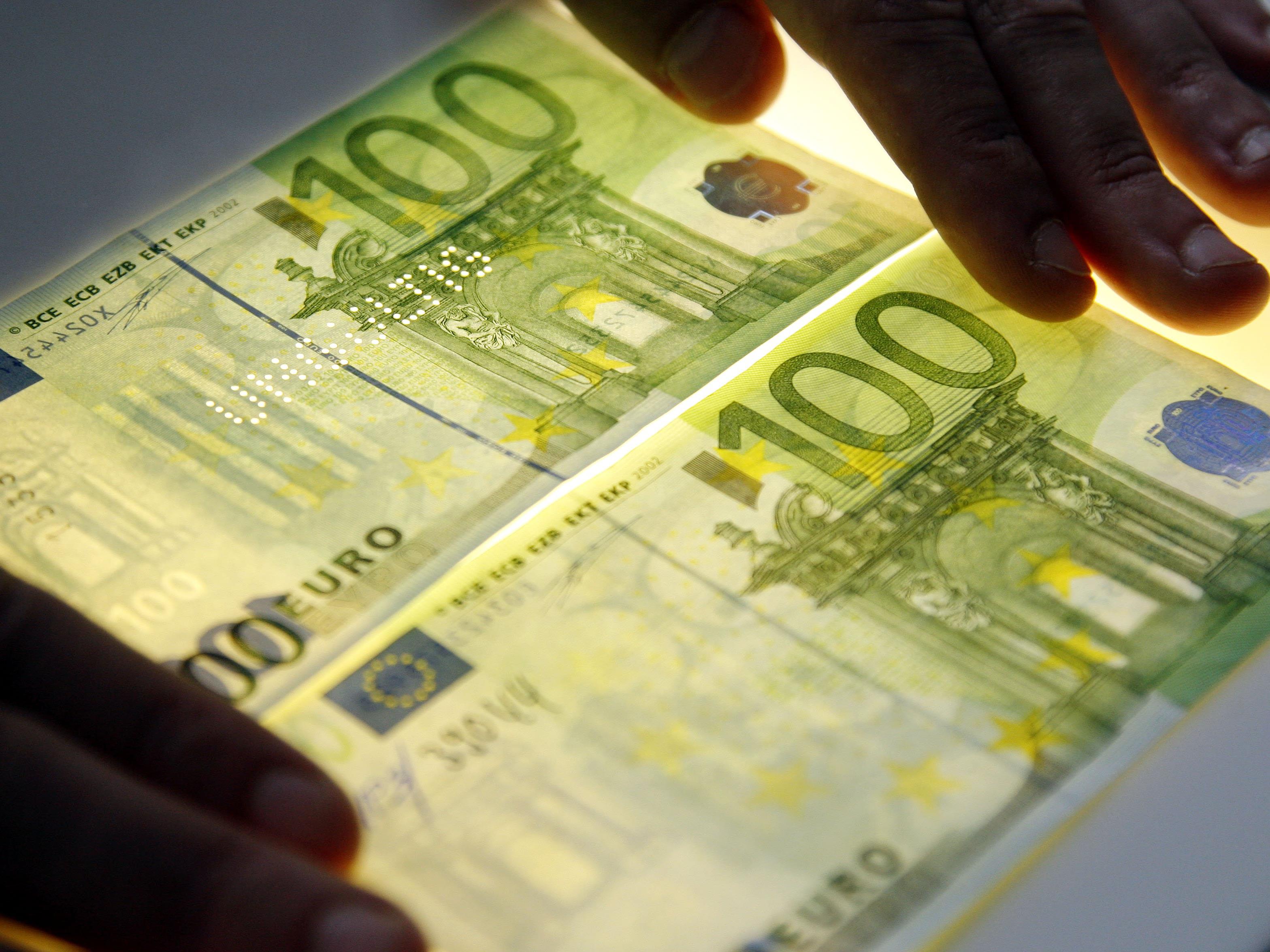 Das Bild zeigt einen echten, rechts unten, und einen gefälschten, links oben, 100 Euro-Schein.