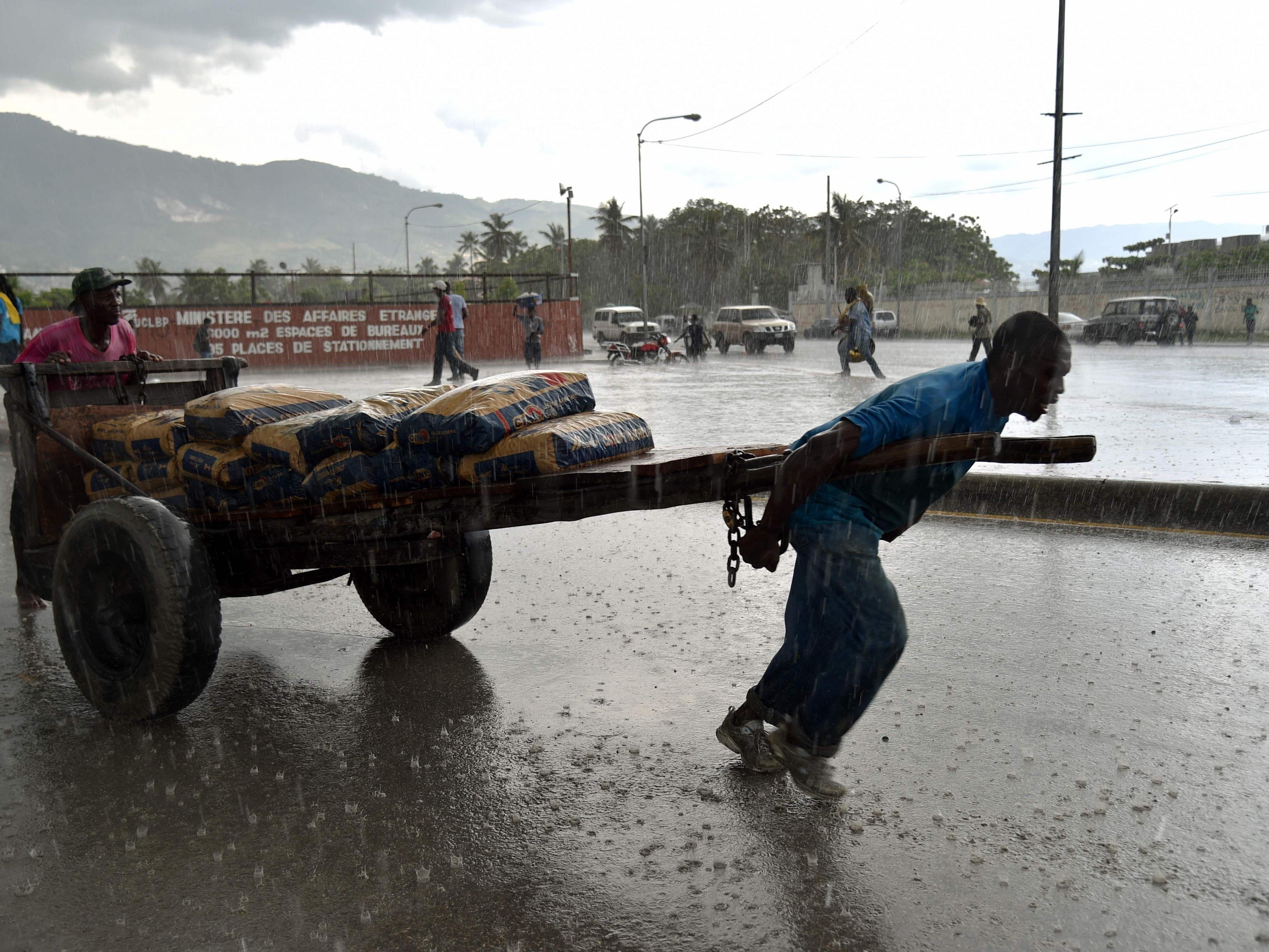 Ein Mann zieht vor dem Parlament in Port-au-Prince einen Karren mit Zement durch den Regen