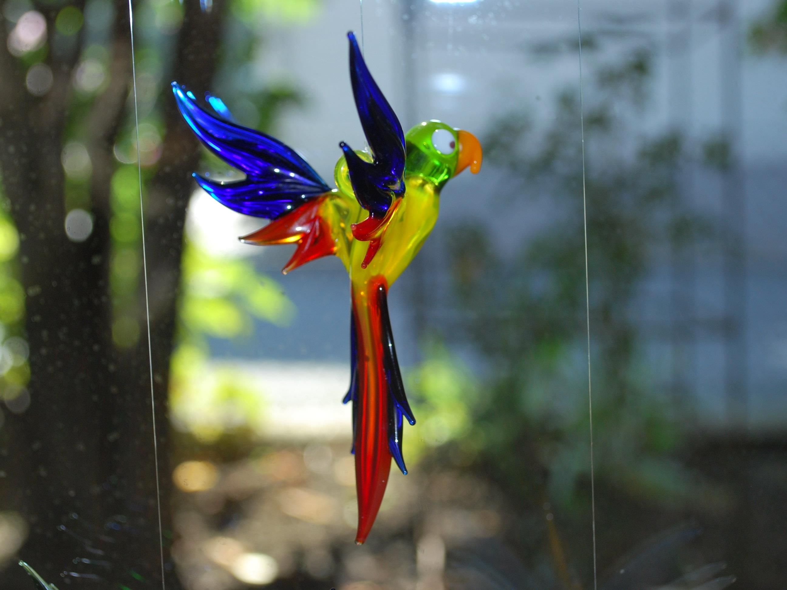 Bunte Vögel aus Glas spiegeln das Sonnenlicht wider.