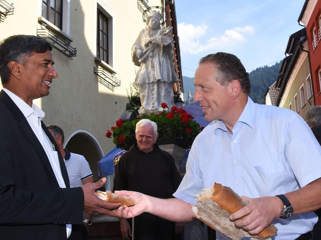 Der Arbeiterkammerpräsident reicht dem Bludenzer Kaplan ein Stück Brot.