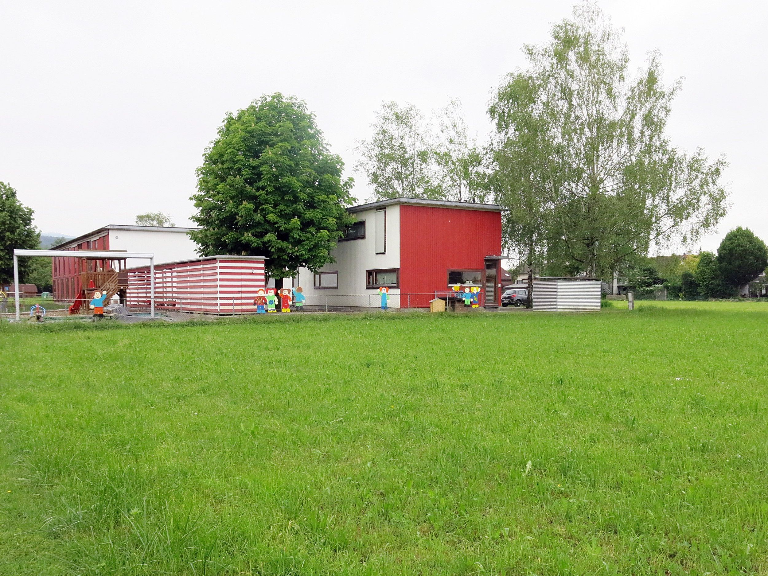 Der neue Kindergartentrakt setzt an der Nordflucht des bestehenden Gebäudes an und führt diesen als eingeschossigen Baukörper. Der neue Kindergartentrakt setzt an der Nordflucht des bestehenden Gebäudes an und führt diesen als eingeschossigen Baukörper.